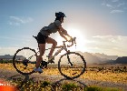 Firefly Radfahrer, der der Sonne entgegenfährt. Berge im Hintergrund. Prärie im Vordergrund. 26128